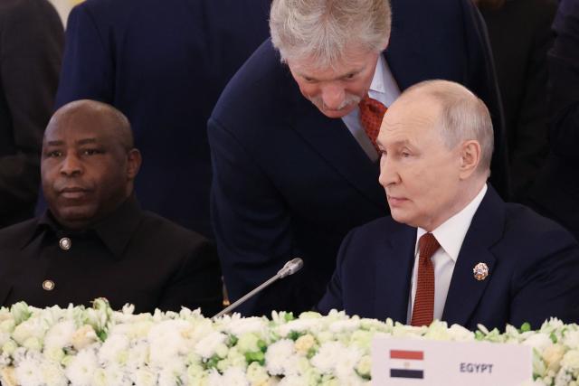 In this pool photograph distributed by the Russian state agency Sputnik, Russia's President Vladimir Putin listens to Kremlin spokesman Dmitry Peskov as Chairperson of the African Union and President of Burundi Evariste Ndayishimiye sits nearby during a plenary session of the third Russia-Africa Summit in Moscow on October 29, 2026. (Photo by Alexander KAZAKOV / Pool / AFP)