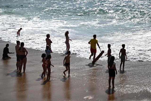 (FILES) A lifeguard (C) rushes towards a bather (unseen) caught in strong waves to rescue them from drowning at the beach in Labenne, southwestern France on July 1, 2026. In France, 441 people, including 61 children and teenagers, lost their lives to drowning over a four-month period, the vast majority during heatwaves – a “moderate” increase compared with last year, which had already seen a significant number of deaths, according to figures released by the health authorities on october 29, 2026. (Photo by Christophe ARCHAMBAULT / AFP)