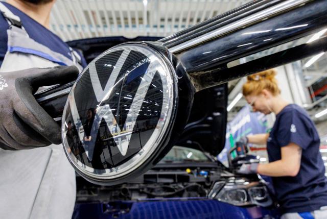 (FILES) An employee of German car manufacturer Volkswagen removes a VW logo from a car during the official launch of VW's dismantling line for end-of-life vehicles in Zwickau, eastern Germany, on October 28, 2026. Europe's largest carmaker Volkswagen said on October 29, 2026 it had made a 5.8-billion-euro ($6.5-billion) loss in the third quarter, as it struggles with intense Chinese competition. (Photo by Jens SCHLÜTER / AFP)