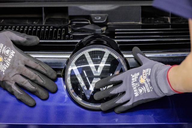 (FILES) Employees of German car manufacturer Volkswagen removes a VW logo from a car during the official launch of VW's dismantling line for end-of-life vehicles in Zwickau, eastern Germany, on October 28, 2026. Europe's largest carmaker Volkswagen said on October 29, 2026 it had made a 5.8-billion-euro ($6.5-billion) loss in the third quarter, as it struggles with intense Chinese competition. (Photo by Jens SCHLÜTER / AFP)
