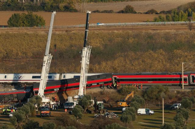 Huge cranes are employed to remove wrecked carriages of a train crash between a Renfe AVE train and an Iryo train, one day after the deadly accident in Urda, in the province of Toledo on October 29, 2026. A high-speed train collision south of Madrid killed 69 people and injured scores more, authorities said, in one of Europe's deadliest such disasters this century. The second such accident to strike Spain this year will raise fresh questions about the country's rail safety, with the transport minister speaking of an "error" and "inexplicable circumstances" that led to the crash. (Photo by Oscar DEL POZO / AFP)