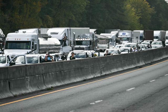 People watch as the motorcade of US President Donald Trump travels along Interstate-77 in Charlotte, North Carolina on October 29, 2026, en route to a campaign event in Rock Hill, South Carolina. (Photo by Kent NISHIMURA / AFP)