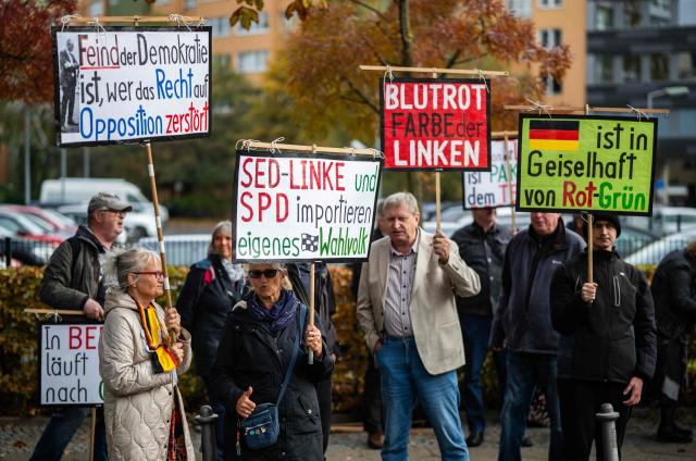Demonstrators display placards outside the headquarters of the Social Democratic Party (SPD) in Berlin on October 29, 2026, criticising the SPD, the Left Party, as well as the Green party who are seeking to form a coalition government in Berlin. (Photo by John MACDOUGALL / AFP)