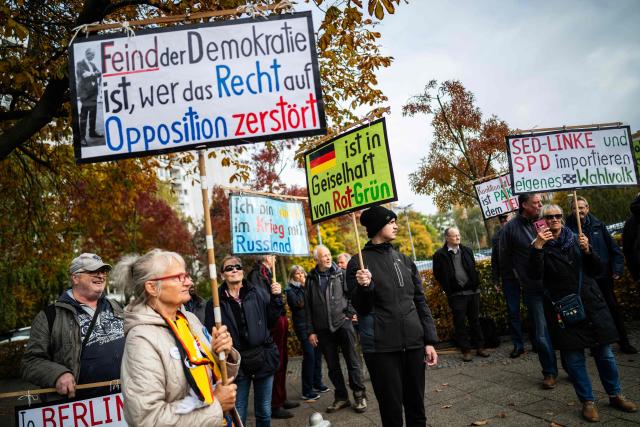 Demonstrators display placards outside the headquarters of the Social Democratic Party (SPD) in Berlin on October 29, 2026, criticising the SPD, the Left Party, as well as the Green party who are seeking to form a coalition government in Berlin. (Photo by John MACDOUGALL / AFP)