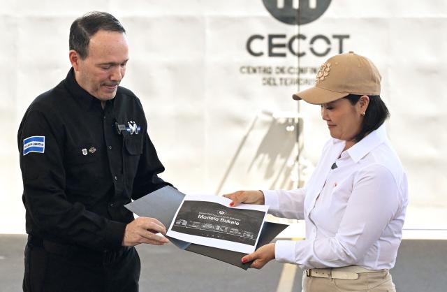 Peru's President Keiko Fujimori receives a document outlining the CECOT prison security model from El Salvador's Minister of Justice and Public Security Gustavo Villatoro during a visit to the CECOT prison in Tecoluca, El Salvador, on October 29, 2026. (Photo by Marvin RECINOS / AFP)