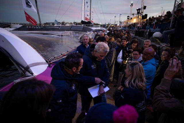 French skipper Louis Burton (L) and French television presenter Denis Brogniart (R) gather prior to the inauguration of the Ultim multihull Armand Thiery, in the harbour of Saint-Malo northwestern France, on October 29, 2026 a few days prior to the start of the Route du Rhum solo sailing race from Saint-Malo, to Pointe-a-Pitre in the French overseas island of Guadeloupe. (Photo by Lou BENOIST / AFP)