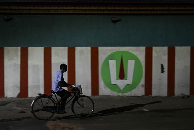 A man rides his bicycle near a temple in the early morning in Chennai on October 30, 2026. (Photo by R. Satish BABU / AFP)