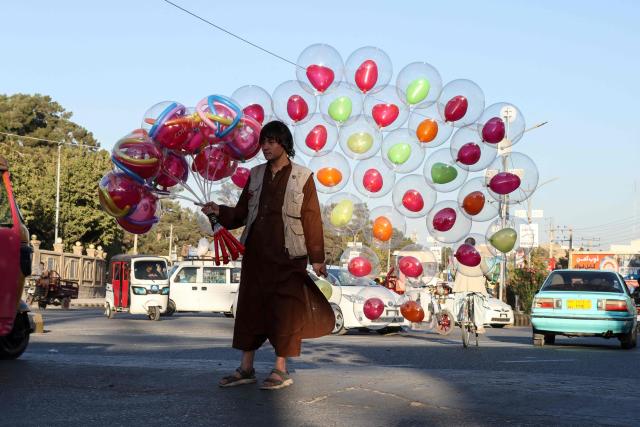 An Afghan boy sells heart-shaped balloons along the road in Herat on October 29, 2026. (Photo by Mohsen KARIMI / AFP)