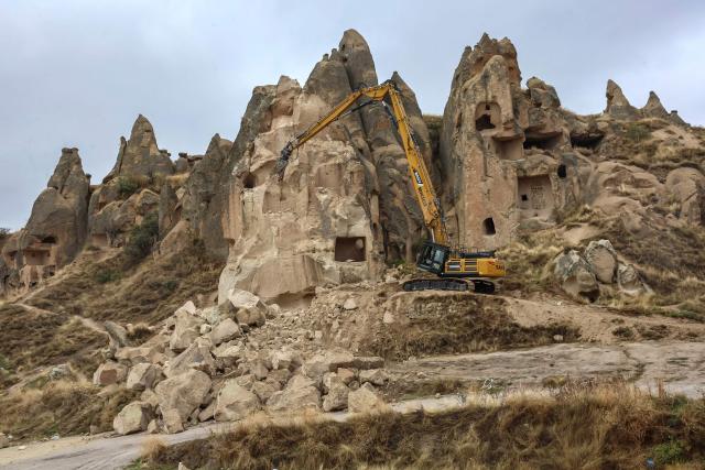 An excavator breaks up rocks for safety reasons at the site of a rock formation that collapsed due to a landslide triggered by heavy rains in Cappadocia district of Nevsehir, on October 30, 2026. A landslide triggered by heavy rainfall caused a rock spire to collapse in Turkey's UNESCO World Heritage-listed Cappadocia region on Thursday, killing at least two people, officials said. (Photo by Adem ALTAN / AFP)