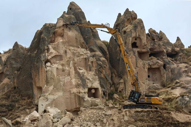 An excavator breaks up rocks for safety reasons at the site of a rock formation that collapsed due to a landslide triggered by heavy rains in Cappadocia district of Nevsehir, on October 30, 2026. A landslide triggered by heavy rainfall caused a rock spire to collapse in Turkey's UNESCO World Heritage-listed Cappadocia region on Thursday, killing at least two people, officials said. (Photo by Adem ALTAN / AFP)