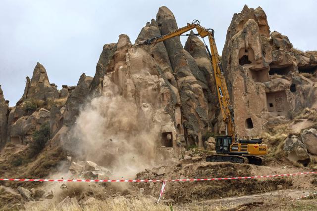 An excavator breaks up rocks for safety reasons at the site of a rock formation that collapsed due to a landslide triggered by heavy rains in Cappadocia district of Nevsehir, on October 30, 2026. A landslide triggered by heavy rainfall caused a rock spire to collapse in Turkey's UNESCO World Heritage-listed Cappadocia region on Thursday, killing at least two people, officials said. (Photo by Adem ALTAN / AFP)