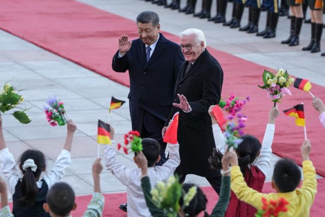 Chinese President Xi Jinping (L) and Germany’s President Frank-Walter Steinmeier (R) wave to children during a welcoming ceremony outside the Great Hall of the People in Beijing on October 30, 2026. (Photo by Kai Naito / POOL / AFP)