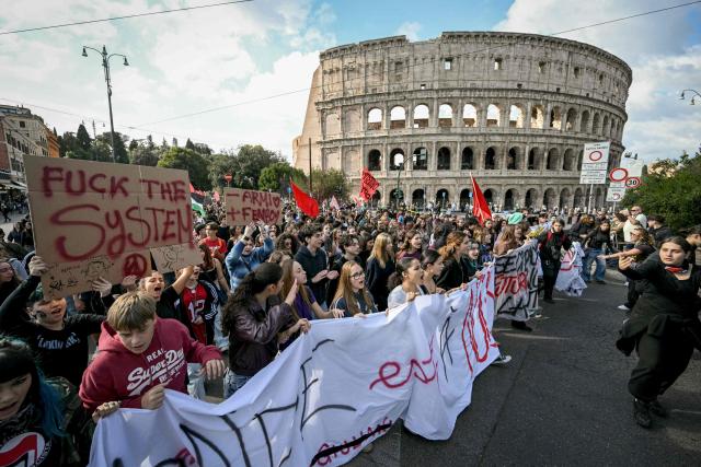 People pass by the Colosseum during a demonstration part of a nationwide day of strikes and protests as school and university students demand more funding for schools and support for housing in Rome on October 30, 2026. Students have been protesting for weeks, setting up tent camps and occupying schools to make their demands heard, matching similar movements across the border in France. The Italian protests have taken place alongside those of truck drivers and farmers over the spike in fuel prices and the cost of living, as well as rising defence spending. (Photo by Andreas SOLARO / AFP)