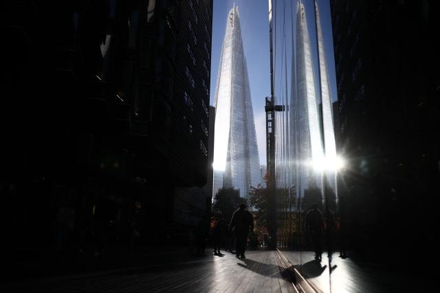 A person walks through an alley way at More London as The Shard skyscraper is reflected in the buildings' windows, on the South Bank of The River Thames in London, on October 30, 2026. (Photo by Henry NICHOLLS / AFP)
