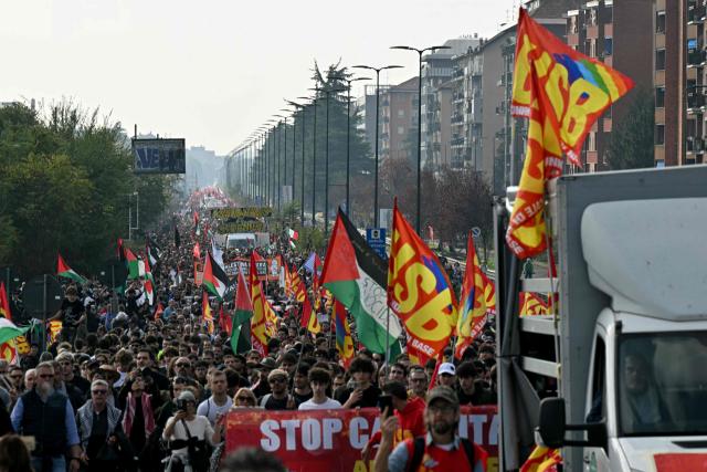 Protesters wave flags of the Unione Sindacale di base as they march during a demonstration part of a nationwide day of strikes and protests as school and university students demand more funding for schools and support for housing, in Milan, northern Italy on October 30, 2026. Students have been protesting for weeks, setting up tent camps and occupying schools to make their demands heard, matching similar movements across the border in France. The Italian protests have taken place alongside those of truck drivers and farmers over the spike in fuel prices and the cost of living, as well as rising defence spending. (Photo by Stefano RELLANDINI / AFP)
