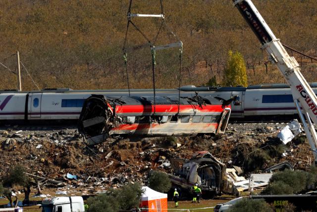 A huge crane lifts one of the wrecked carriages of a train crash between a Renfe AVE train and an Iryo train, two days after the deadly accident in Urda, in the province of Toledo on October 30, 2026. A high-speed train collision south of Madrid killed 69 people and injured scores more, authorities said, in one of Europe's deadliest such disasters this century. The second such accident to strike Spain this year will raise fresh questions about the country's rail safety, with the transport minister speaking of an "error" and "inexplicable circumstances" that led to the crash. (Photo by Oscar DEL POZO / AFP)