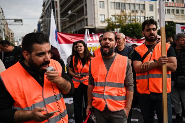 Seafarers and dockworkers chant slogans as they take part in a march from the port of Piraeus, near Athens, towards Greece's Ministry of Maritime Affairs on October 30, 2026, during a 24-hours strike held as part of an international day of action by dockworkers against the transport of weapons and military equipment through ports. Ships remained docked at seven Greek ports, including Piraeus, Rafina and Lavrio, as seafarers' unions demanded that vessels stop carrying military cargo and that crews no longer be sent to conflict zones, as well as higher wages and better working conditions. Organisers said more than 100 ports in several countries, including Italy and France, joined the action. (Photo by Aris MESSINIS / AFP)