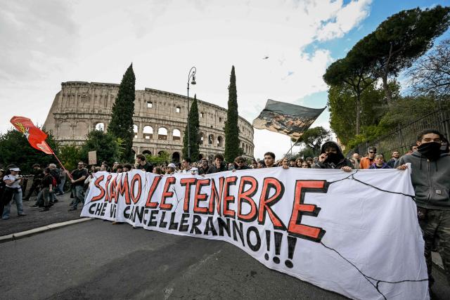 People march behind a banner reading in Italian "We are the darkness that will wipe you out !!!" during a demonstration part of a nationwide day of strikes and protests as school and university students demand more funding for schools and support for housing in Rome on October 30, 2026. Students have been protesting for weeks, setting up tent camps and occupying schools to make their demands heard, matching similar movements across the border in France. The Italian protests have taken place alongside those of truck drivers and farmers over the spike in fuel prices and the cost of living, as well as rising defence spending. (Photo by Andreas SOLARO / AFP)