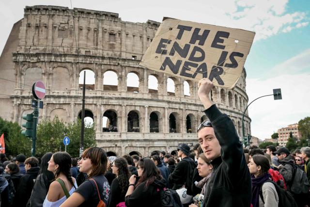 A person holds a placard reading in English "the end is near" during a demonstration part of a nationwide day of strikes and protests as school and university students demand more funding for schools and support for housing in Rome on October 30, 2026. Students have been protesting for weeks, setting up tent camps and occupying schools to make their demands heard, matching similar movements across the border in France. The Italian protests have taken place alongside those of truck drivers and farmers over the spike in fuel prices and the cost of living, as well as rising defence spending. (Photo by Alberto PIZZOLI / AFP)