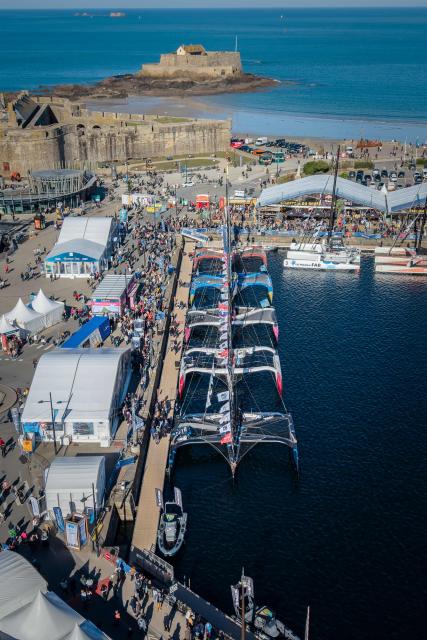 This aerial photograph taken on October 30, 2026 shows the village of the Route du Rhum destination Guadeloupe and multihulls Ocean Fifty class moored in the harbour of Saint-Malo northwestern France, a few days prior to the start of the Route du Rhum solo sailing. From Saint-Malo in Brittany to Pointe-a-Pitre in Guadeloupe, over 100 skippers across 6 classes will take the start on November 1, 2026, in this solo transatlantic sailing race. (Photo by Lou BENOIST / AFP)