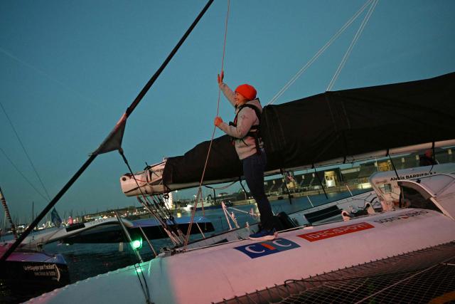 French skipper Alexia Barrier, waves aboard of her "Idec Sport - CIC" Ultim class as she passes through the Naye lock of Saint-Malo's harbour, to moor of the coast of Saint-Malo northwestern France on October 30, 2026 a few days prior to the start of the Route du Rhum solo sailing race from Saint-Malo, to Pointe-a-Pitre in the French overseas island of Guadeloupe.  (Photo by Loic VENANCE / AFP)