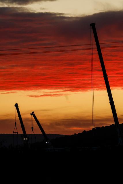 Huge cranes employed to remove the wrecked carriages of a deadly train crash are silhouetted at sunset two days after the accident in Urda, in the province of Toledo on October 30, 2026. A high-speed train collision south of Madrid killed 69 people and injured scores more on October 28, 2026 in one of Europe's deadliest such disasters this century. (Photo by Oscar DEL POZO / AFP)
