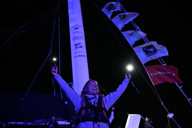 French skipper Alexia Barrier, waves aboard of her "Idec Sport - CIC" Ultim class as she passes through the Naye lock of Saint-Malo's harbour, to moor of the coast of Saint-Malo northwestern France on October 30, 2026 a few days prior to the start of the Route du Rhum solo sailing race from Saint-Malo, to Pointe-a-Pitre in the French overseas island of Guadeloupe.  (Photo by Loic VENANCE / AFP)