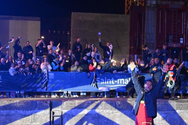 "Liamm" Ultim class French skipper Guirec Soudee waves to the crowd as he enters the lock to leave the harbor of Saint-Malo Western France, on October 30, 2026, two days before the start of the 13th Route du Rhum - Destination Guadeloupe. From Saint-Malo in Brittany to Pointe-a-Pitre in Guadeloupe, 115 skippers across 6 classes will take the start on November 1, 2026 in this solo transatlantic sailing race. (Photo by Sebastien Salom-Gomis / AFP)