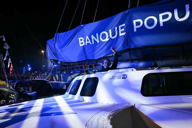 French skipper Armel Le Cleac'h waves aboard of his "Maxi Banque Populaire XI" Ultim Class passing through the lock of Saint-Malo's harbour, to moor of the coast of Saint-Malo northwestern France on October 30, 2026 a few days prior to the start of the Route du Rhum solo sailing race from Saint-Malo, to Pointe-a-Pitre in the French overseas island of Guadeloupe.  (Photo by LOU BENOIST / AFP)