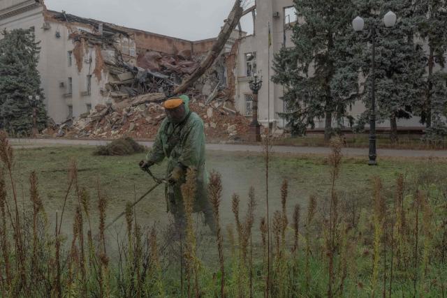 A communal worker cuts grass next to the Kherson Regional State Administration building, which was destroyed in previous Russian air attacks, during a temporary ceasefire in the southern Kherson region at Freedom Square in the city of Kherson, southern Ukraine, on October 30, 2026, amid the Russian invasion of Ukraine. The respite from a fragile ceasefire in Oleshky, a Russian-occupied town in southern Ukraine ravaged by food and medicine shortages, to pave the way for evacuations and humanitarian aid deliveries and due to end on November 1 evening, has also given residents in the major southern Ukrainian city of Kherson relief from daily drone attacks. The truce has held despite unabated attacks elsewhere in Ukraine. (Photo by Roman PILIPEY / AFP)