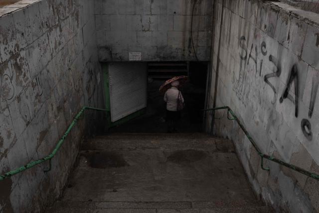 A person walks down to an underground passage during a temporary ceasefire in the southern Kherson region, in the city of Kherson, southern Ukraine, on October 30, 2026, amid the Russian invasion of Ukraine. The respite from a fragile ceasefire in Oleshky, a Russian-occupied town in southern Ukraine ravaged by food and medicine shortages, to pave the way for evacuations and humanitarian aid deliveries and due to end on November 1 evening, has also given residents in the major southern Ukrainian city of Kherson relief from daily drone attacks. The truce has held despite unabated attacks elsewhere in Ukraine. (Photo by Roman PILIPEY / AFP)