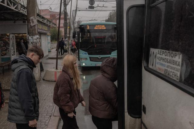 People get on a minibus at a bus station, on a road covered with anti-drone nets during a temporary ceasefire in the southern Kherson region, in the city of Kherson, southern Ukraine, on October 30, 2026, amid the Russian invasion of Ukraine. The respite from a fragile ceasefire in Oleshky, a Russian-occupied town in southern Ukraine ravaged by food and medicine shortages, to pave the way for evacuations and humanitarian aid deliveries and due to end on November 1 evening, has also given residents in the major southern Ukrainian city of Kherson relief from daily drone attacks. The truce has held despite unabated attacks elsewhere in Ukraine. (Photo by Roman PILIPEY / AFP)