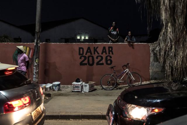 Bystanders watch as a torchbearer carries the Youth Olympic Flame on the eve of the opening ceremony of the Youth Olympic Games in Dakar on October 30, 2026. Over the course of two weeks some 2,700 athletes aged 17 or younger are expected to compete across 25 sports, including Russians who are returning to the Games following a ban. Events ranging from athletics to beach wrestling, rugby sevens to breaking will be held across eight venues in three locations (Photo by PATRICK MEINHARDT / AFP)