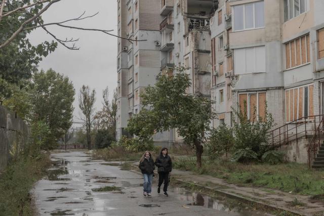 People walk past a residential building which was heavily damaged in previous air attacks during a temporary ceasefire in the southern Kherson region, in the city of Kherson, southern Ukraine, on October 30, 2026, amid the Russian invasion of Ukraine. The respite from a fragile ceasefire in Oleshky, a Russian-occupied town in southern Ukraine ravaged by food and medicine shortages, to pave the way for evacuations and humanitarian aid deliveries and due to end on November 1 evening, has also given residents in the major southern Ukrainian city of Kherson relief from daily drone attacks. The truce has held despite unabated attacks elsewhere in Ukraine. (Photo by Roman PILIPEY / AFP)