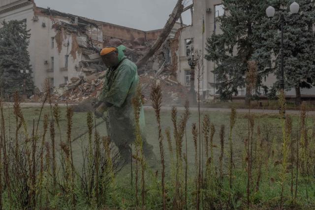 A communal worker cuts grass next to the Kherson Regional State Administration building, which was destroyed in previous air attacks, during a temporary ceasefire in the southern Kherson region, in the city of Kherson, southern Ukraine, on October 30, 2026, amid the Russian invasion of Ukraine. The respite from a fragile ceasefire in Oleshky, a Russian-occupied town in southern Ukraine ravaged by food and medicine shortages, to pave the way for evacuations and humanitarian aid deliveries and due to end on November 1 evening, has also given residents in the major southern Ukrainian city of Kherson relief from daily drone attacks. The truce has held despite unabated attacks elsewhere in Ukraine. (Photo by Roman PILIPEY / AFP)