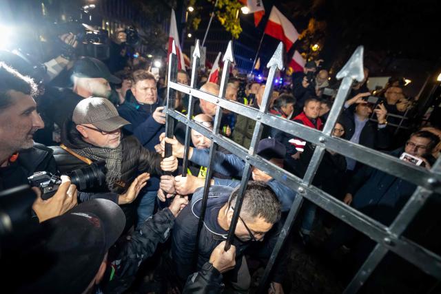 Protesters force open a metal gate leading to the courtyard outside the headquarters of Poland's Constitutional Court after police blocked access to the building in Warsaw, Poland on October 30, 2026. Poland's President Karol Nawrocki called off a visit to Africa in mid-flight as riot police deployed around the country's constitutional court on October 30 following the suspension of its chief justice in a battle between the centrist government and the nationalist right. Dozens of police guarded the entrance to the court as followers of the opposition right-wing Law and Justice party (PiS) protested the ousting of constitutional court president Bogdan Swieczkowski. (Photo by Wojtek RADWANSKI / AFP)
