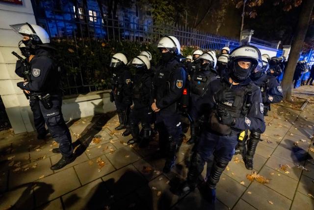Police officers stand on alert as protesters gather outside the headquarters of Poland's Constitutional Court in Warsaw after police blocked access to the building on October 30, 2026. Poland's President Karol Nawrocki called off a visit to Africa in mid-flight as riot police deployed around the country's constitutional court on October 30 following the suspension of its chief justice in a battle between the centrist government and the nationalist right. Dozens of police guarded the entrance to the court as followers of the opposition right-wing Law and Justice party (PiS) protested the ousting of constitutional court president Bogdan Swieczkowski. (Photo by Wojtek RADWANSKI / AFP)