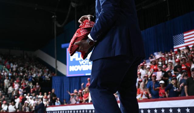 A campaign aide tosses MAGA hats to attendees ahead of US President Donald Trump's remarks at a midterm campaign rally at the Ocean Center in Daytona Beach, Florida, on October 30, 2026. (Photo by Brendan SMIALOWSKI / AFP)