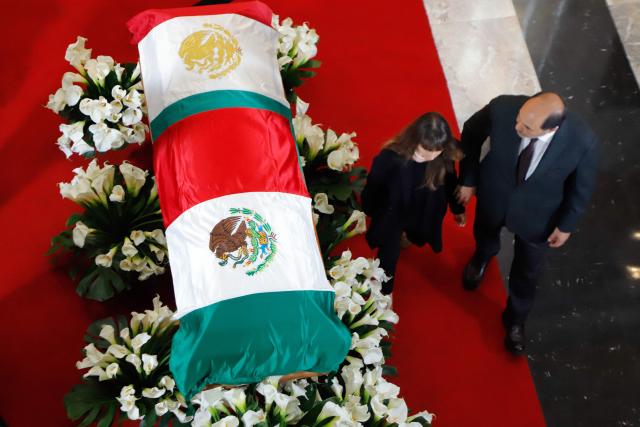 Camila Cardenas (L) and Lazaro Cardenas, children of former Mexican presidential candidate Cuauhtemoc Cardenas, walk past their father's coffin, draped in the Mexican flag, during a tribute ceremony at the Palace of Fine Arts in Mexico City on October 30, 2026. Hundreds of Mexicans paid tribute to Cardenas, a three-time presidential candidate, former Mexico City mayor and leading figure of Mexico's modern left, who died on October 28 at the age of 92. (Photo by Barny GOMEZ / AFP)
