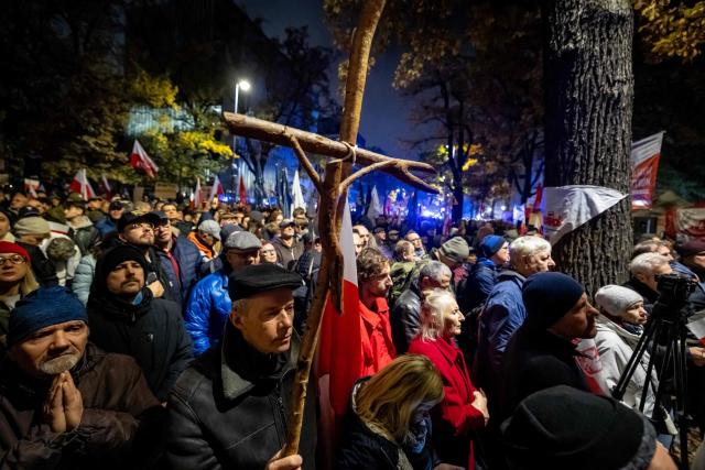 A man holds a cross as protesters gather outside the headquarters of the Poland's Constitutional Court in Warsaw after police blocked access to the court building on October 30, 2026. Poland's President Karol Nawrocki called off a visit to Africa in mid-flight as riot police deployed around the country's constitutional court on October 30 following the suspension of its chief justice in a battle between the centrist government and the nationalist right. Dozens of police guarded the entrance to the court as followers of the opposition right-wing Law and Justice party (PiS) protested the ousting of constitutional court president Bogdan Swieczkowski. (Photo by Wojtek RADWANSKI / AFP)
