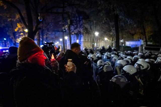A woman holds an electric candle as protesters gather outside the headquarters of Polands Constitutional Court in Warsaw after police blocked access to the court building on October 31, 2026. Poland's President Karol Nawrocki called off a visit to Africa in mid-flight as riot police deployed around the country's constitutional court on October 30 following the suspension of its chief justice in a battle between the centrist government and the nationalist right. Dozens of police guarded the entrance to the court as followers of the opposition right-wing Law and Justice party (PiS) protested the ousting of constitutional court president Bogdan Swieczkowski. (Photo by Wojtek RADWANSKI / AFP)