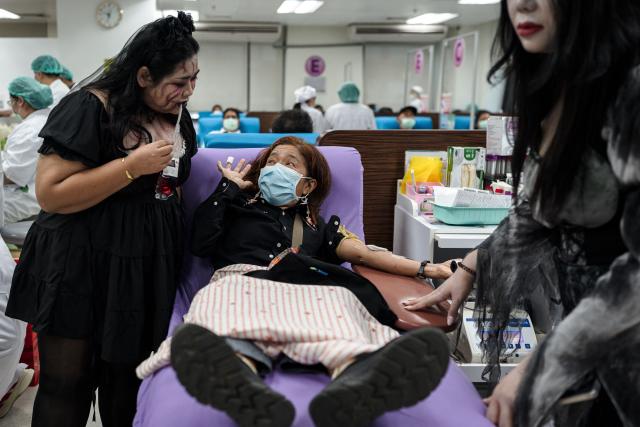 Thai Red Cross staff members dressed in Halloween costumes pose with a woman donating blood at the National Blood Center of the Thai Red Cross Society in Bangkok on October 31, 2026. (Photo by Chanakarn Laosarakham / AFP)