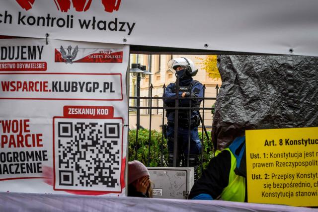 A police officer dressed in riot gear stands outside the headquarters of Poland's Constitutional Court as protesters gather in protest in Warsaw on October 31, 2026. Poland's President Karol Nawrocki called off a visit to Africa in mid-flight as riot police deployed around the country's constitutional court on October 30 following the suspension of its chief justice in a battle between the centrist government and the nationalist right. Dozens of police guarded the entrance to the court as followers of the opposition right-wing Law and Justice party (PiS) protested the ousting of constitutional court president Bogdan Swieczkowski. (Photo by Mladen ANTONOV / AFP)