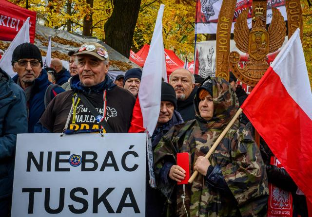 Protesters with flags and a poster reading "Don't fear Tusk" gather outside the headquarters of Poland's Constitutional Court in Warsaw after police blocked access to the building on October 31, 2026. Poland's President Karol Nawrocki called off a visit to Africa in mid-flight as riot police deployed around the country's constitutional court on October 30 following the suspension of its chief justice in a battle between the centrist government and the nationalist right. Dozens of police guarded the entrance to the court as followers of the opposition right-wing Law and Justice party (PiS) protested the ousting of constitutional court president Bogdan Swieczkowski. (Photo by Mladen ANTONOV / AFP)