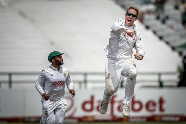 TOPSHOT - South Africa's Simon Harmer (R) jumps next to South Africa's Temba Bavuma (L) to celebrate the dismissal of Australia's Alex Carey on day five of the third Test match between South Africa and Australia at Newlands stadium in Cape Town on October 31, 2026. (Photo by Marco Longari / AFP)