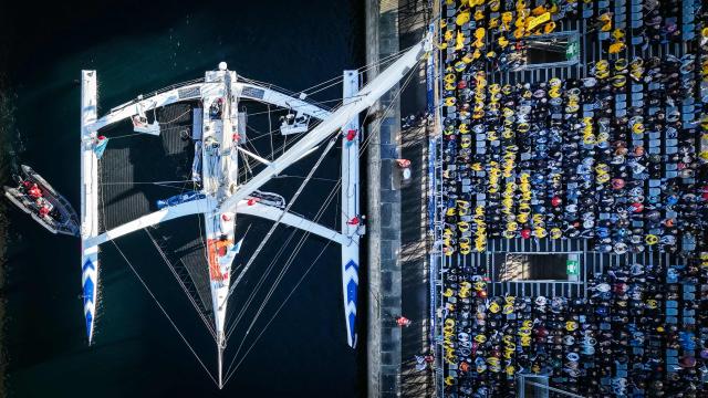 This aerial photograph shows French skipper Eric Peron sailing his vintage multihull "French Touch - Oceania Hote" through the Naye lock of Saint-Malo's harbour, to moor of the coast of Saint-Malo northwestern France on October 31, 2026 a few days prior to the start of the Route du Rhum solo sailing race from Saint-Malo, to Pointe-a-Pitre in the French overseas island of Guadeloupe.  (Photo by LOU BENOIST / AFP)