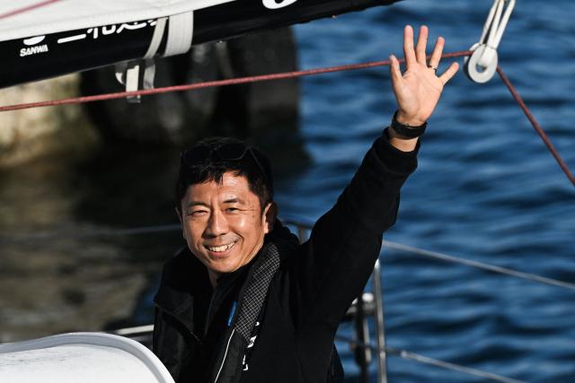 Japanese sailor Masa Suzuki reacts from aboard his "Milai 22" IMOCA Class through the lock of Saint-Malo's harbour to moor off the coast of Saint-Malo, northwestern France on October 31, 2026 on the eve of the start of the Route du Rhum solo sailing race from Saint-Malo, to Pointe-a-Pitre in the French overseas island of Guadeloupe. (Photo by Sebastien Salom-Gomis / AFP)