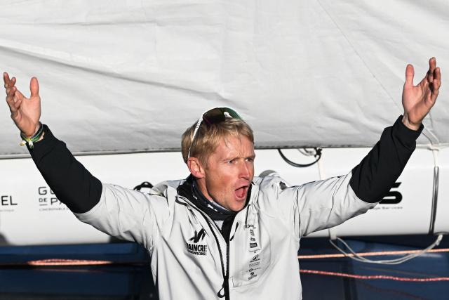 French sailor Maxime Sorel reacts from aboard his "NC" IMOCA Class through the lock of Saint-Malo's harbour to moor off the coast of Saint-Malo, northwestern France on October 31, 2026 on the eve of the start of the Route du Rhum solo sailing race from Saint-Malo, to Pointe-a-Pitre in the French overseas island of Guadeloupe. (Photo by Sebastien Salom-Gomis / AFP)