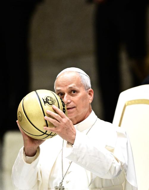 Pope Leo XIV receives a ball as a gift during an audience with delegations from Villanova University and the University of Notre Dame at the Paul VI Audience Hall in the Vatican on October 31, 2026. (Photo by TIZIANA FABI / AFP)