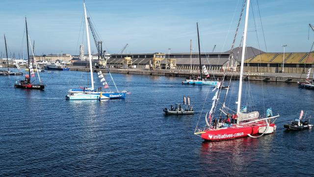 This aerial photograph shows skipper Violette Dorange sailing her Imoca Initiative Cњur  past Saint-Malo's harbour off the coast of Saint-Malo northwestern France on October 31, 2026 on the eve of the start of the Route du Rhum solo sailing race from Saint-Malo, to Pointe-a-Pitre in the French overseas island of Guadeloupe. (Photo by LOU BENOIST / AFP)